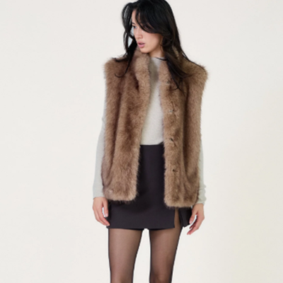 Colete castanho de pelo sintético com botões usado por mulher com camisola e mini saia preta