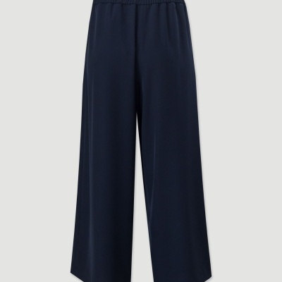 Calças largas azuis escuras com cós elástico sobre fundo cinzento claro