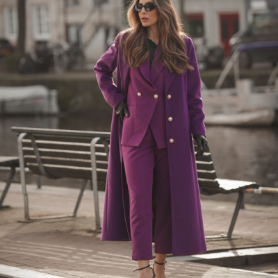 Mulher com conjunto roxo, luvas pretas e óculos escuros junto a canal urbano