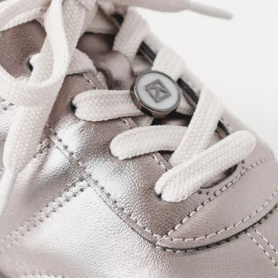 Ténis de criança prateado com atacadores brancos e botão redondo no atacador