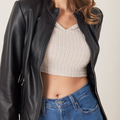 Casaco preto de couro sobre top branco de malha canelada e calças de ganga azul