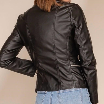 Casaco curto preto de pele visto de costas, com calças de ganga azul claro