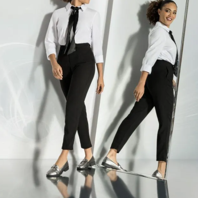 Duas mulheres com roupas formais pretas e brancas e sapatos prateados numa sala espelhada