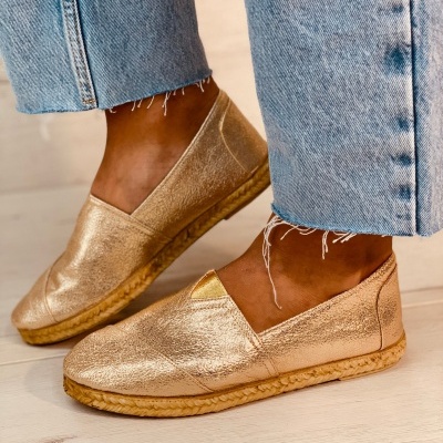 Sapatos alpercatas dourados com sola clara e calças de ganga azul claro