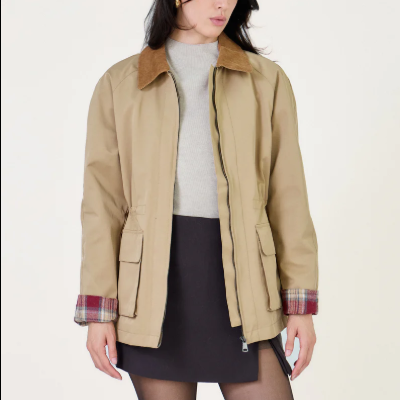 Casaco bege com gola castanha, bolsos e padrão xadrez nas mangas.