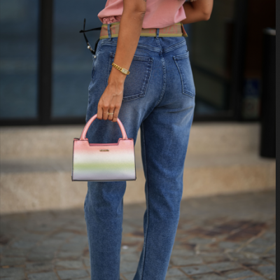 Mulher de costas com calças de ganga azul clara e mala pequena colorida