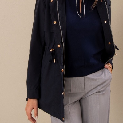 Mulher veste casaco azul escuro, polo azul marinho e calças cinza claras.