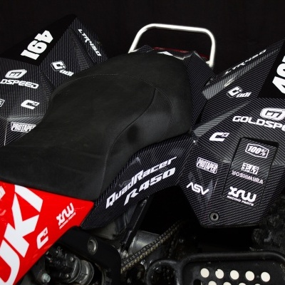 Mota todo-o-terreno com detalhes em carbono preto, assento preto, partes vermelhas e inscrições brancas