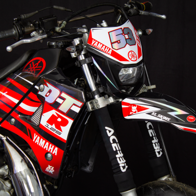 Motociclo Yamaha preto, vermelho e branco com gráficos e textos visíveis