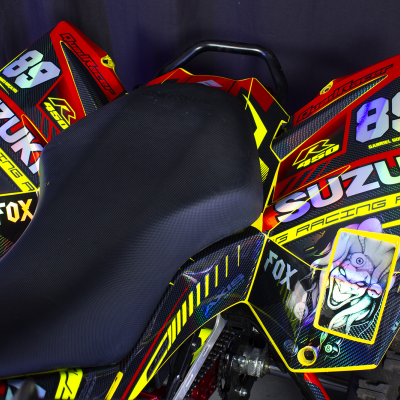 Quad Suzuki R 450 vermelho, amarelo e preto com assento texturizado preto e adesivos coloridos