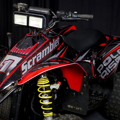 Quadriciclo preto e vermelho com detalhes amarelos e faróis retangulares