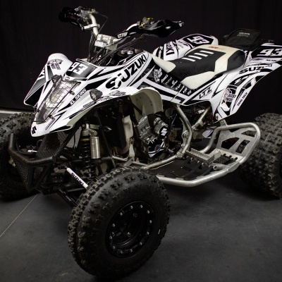 Quadriciclo preto e branco Suzuki com gráficos e número 53 em estúdio com fundo preto