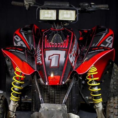 Veículo todo-o-terreno vermelho e preto com suspensão amarela e texto 'Fighter' e número '1'