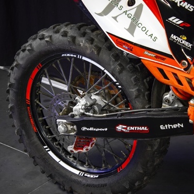 Roda traseira de mota de todo-o-terreno com suspensão laranja e detalhes de marcas.