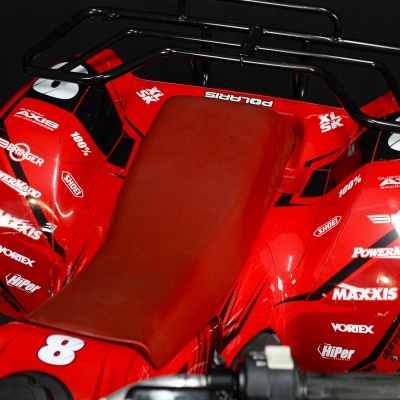 Quadriciclo vermelho com assento de couro vermelho e várias marcas impressas e o número 8 no painel