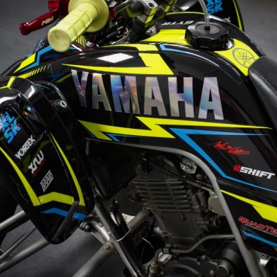 Motocicleta Yamaha preta com detalhes amarelos e azuis e adesivos coloridos