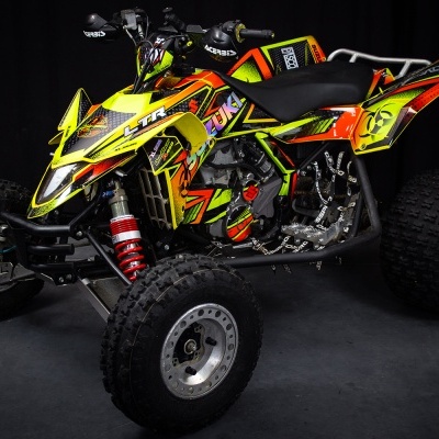 Quadriciclo desportivo amarelo e preto com padrões coloridos e pneus off-road