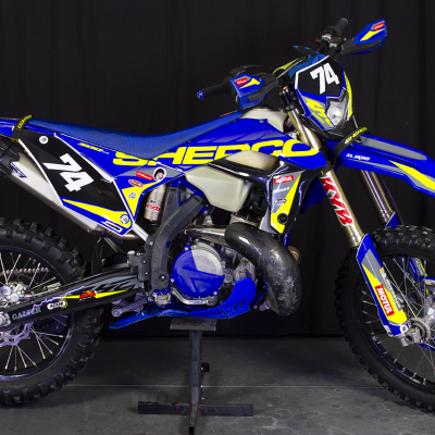 Motocross Sherco azul com número 74 em fundo preto