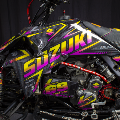 Quad Suzuki preto com gráficos amarelos, roxos e rosas e suspensão Elka