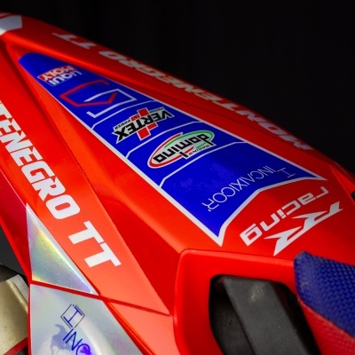 Parte de motocicleta vermelha com adesivos e detalhes em tecido azul