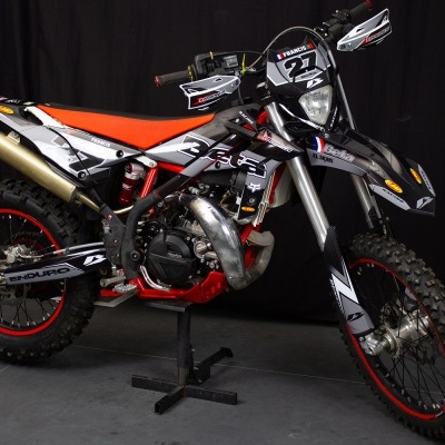 Motocross preta, branca e vermelha com pneus de terra e detalhes vermelhos.