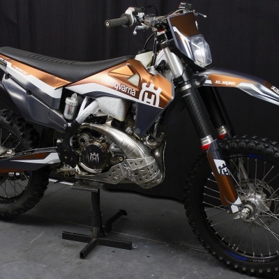 Motocross Husqvarna azul, laranja e prata em suporte metálico