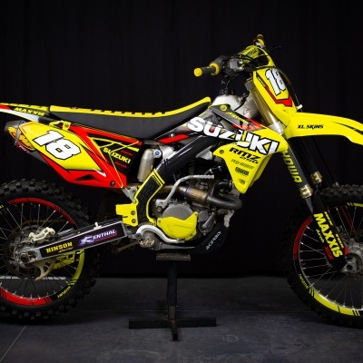 Motocross Suzuki amarela com número 18 e pneus Maxxis
