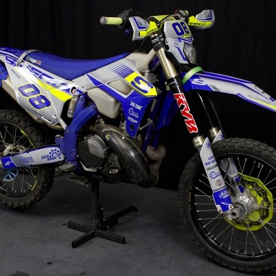 Mota de motocross azul, branca, amarela e preta com números 08 e marca Sherco