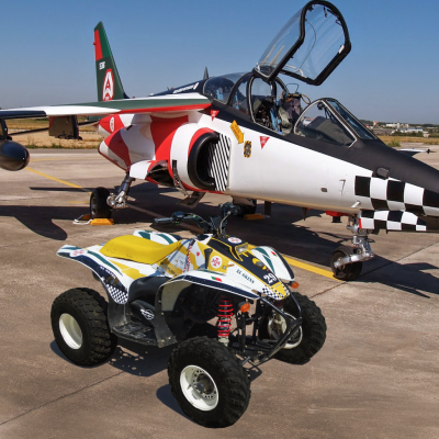 Quadriciclo colorido em frente a avião militar com padrão xadrez