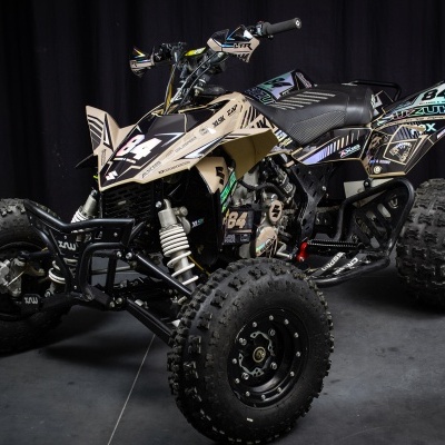Quadriciclo off-road preto e bege com número 94 sobre fundo escuro