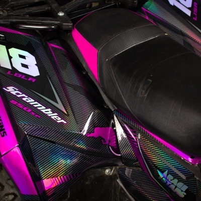 Veículo todo-o-terreno com design em carbono preto e detalhes rosa e assento preto.