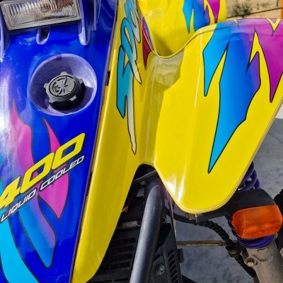 Quad amarelo e azul com texto e estrutura metálica em ambiente exterior