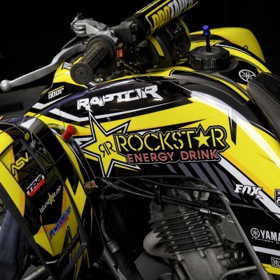 Quad amarelo com decoração e logotipos da Rockstar Energy Drink e outras marcas em fundo escuro