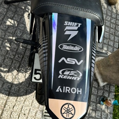 Parte traseira de motocicleta preta com logotipos e assento preto