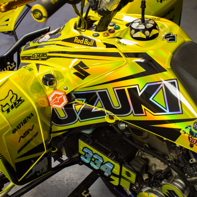 Moto Suzuki amarela com grafismos e textos pretos e azuis, vista em oficina