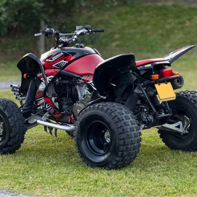 Quadriciclo vermelho e preto com pneus largos em relva