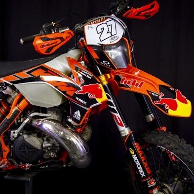 Motocross KTM laranja com grafismos e número 27 em fundo preto