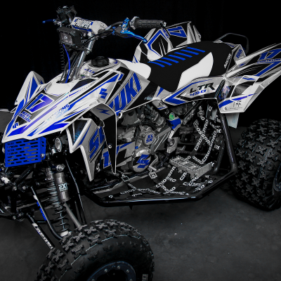 Quadriciclo todo-o-terreno branco, preto e azul com pneus cravados e assento acolchoado.