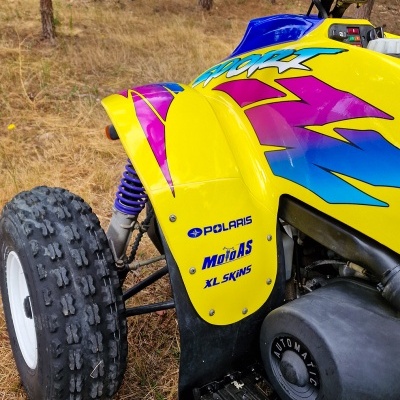 Quadriciclo amarelo colorido com detalhes azuis e rosa no bosque