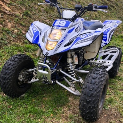 Quad Suzuki Z400 branco e azul em relva com colina de terra ao fundo