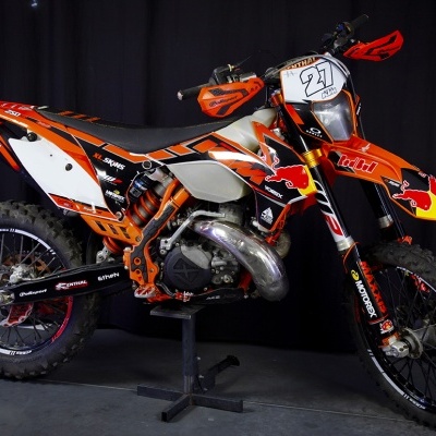 Motocross KTM 250 laranja com número 27 e adesivos em fundo preto