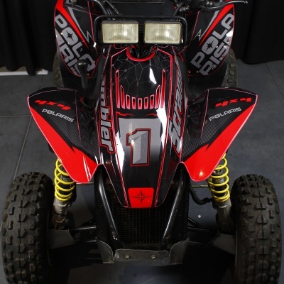 Veículo todo-o-terreno vermelho e preto com suspensão amarela e luzes duplas quadradas