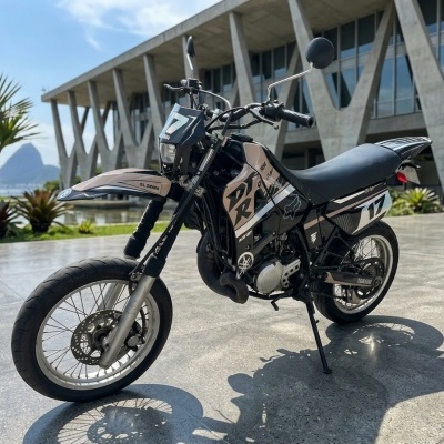 Motocicleta Yamaha preta e bege com inscrições DXR e número 17 em ambiente exterior