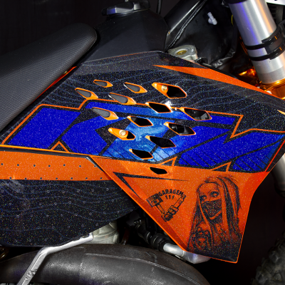 Parte lateral de mota de suspensão com painel laranja e azul metálico e assento preto texturizado