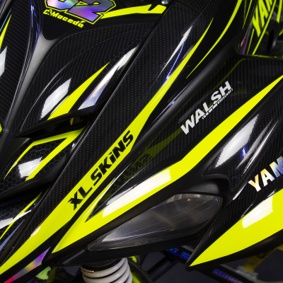 Parte dianteira de mota com padrões amarelo fluorescente e preto carbono e várias marcas impressas