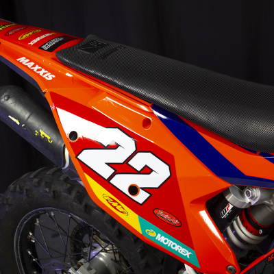 Detalhe da parte traseira de motocross laranja com número 22 e autocolantes