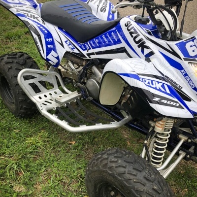 Quad Suzuki Z400 branco e azul com números 69, assento preto e azul, sobre relva e caminho de terra