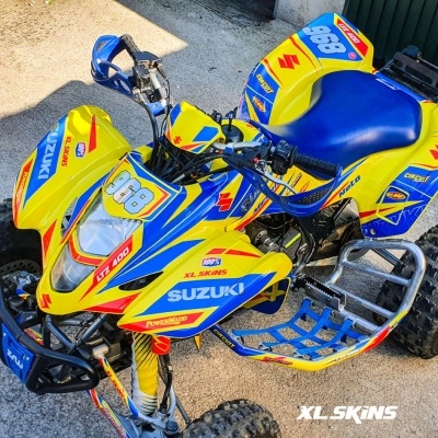 Quad Suzuki LTZ 400 amarelo e azul estacionado em piso de cimento perto de muro verde