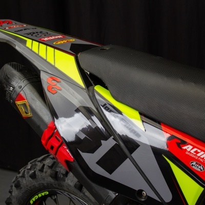Parte traseira de mota de cross com cores preta, cinza, amarelo e vermelho