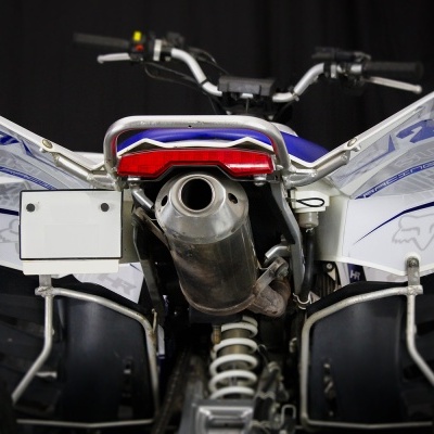 Quadriciclo branco e azul visto de trás com escapamento metálico